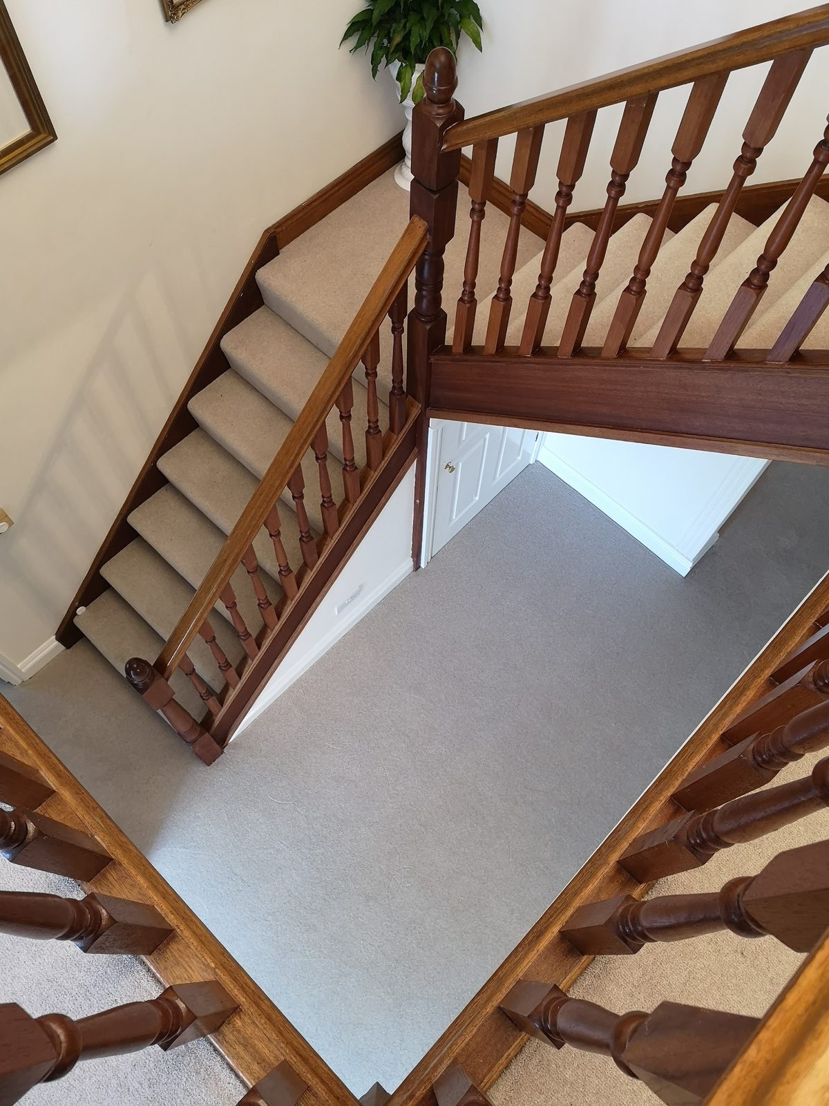 Light grey carpet fitted across a landing beside an oak staircase