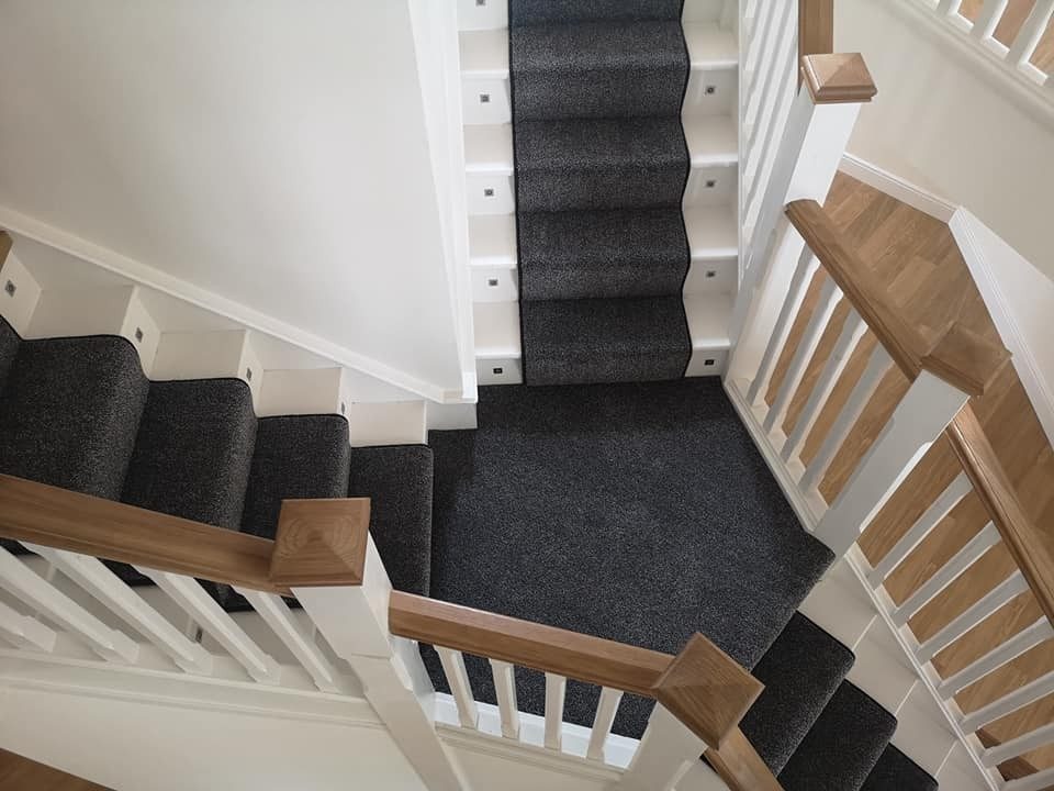 Charcoal stair runner with white spindles and an oak handrail, seen from above