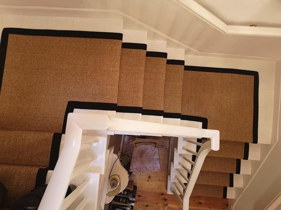 Natural sisal-look stair runner with a black border, seen from the landing above