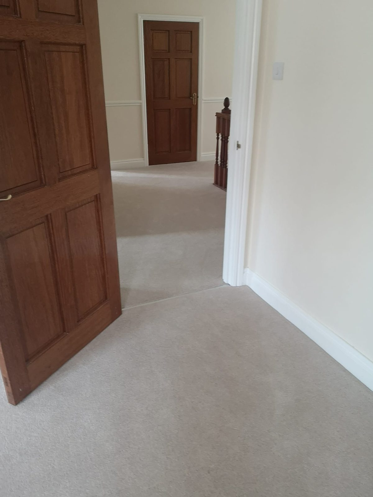 Cream carpet fitted through a hallway with wooden doors